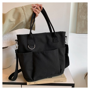 Detail showing thick black canvas tote bag with adjustable shoulder strap and metal D-ring