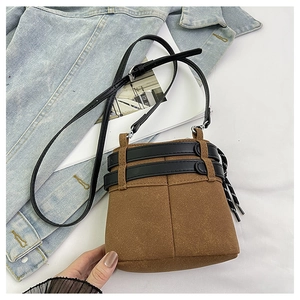 Dettaglio mini borsa a secchiello in camoscio marrone con cinturini in pelle nera