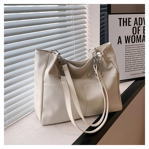 Close-up of cream white PU leather tote bag with silver hardware on a sunny windowsill