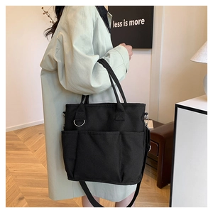 Detail of black canvas tote bag showing side D-ring and multi-pocket functional design