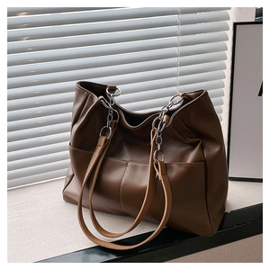 Detailed macro of dark brown tote bag with metal chain strap and soft leather texture