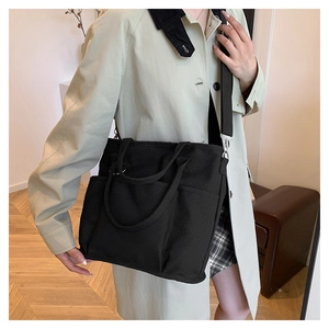 Lifestyle shot of black canvas tote bag with multiple pockets and detachable strap