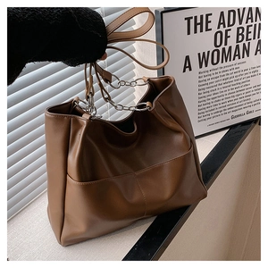 Detailed close-up of brown PU leather tote bag with silver chain handle and front pocket