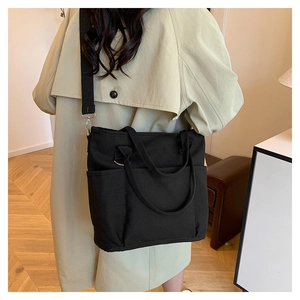 Detail of black canvas tote bag with adjustable shoulder strap and utility pockets