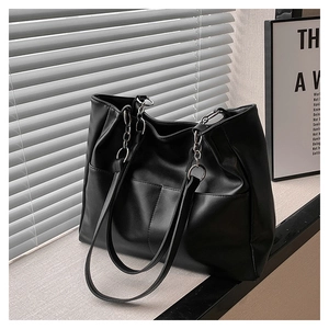 Detail of black PU leather tote with silver metal chain strap and large front pockets