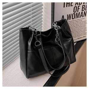 Close-up of black leather tote bag with silver chain straps and vertical stitching