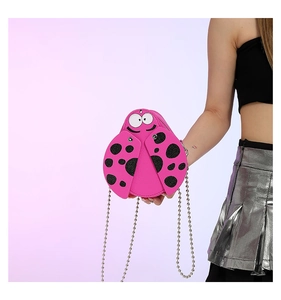 Close-up of cute pink ladybug cross-body bag with bead chain and polka dots