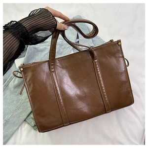 Nahaufnahme der braunen Vintage-Einkaufstasche mit Nieten und eleganten Seitenquasten