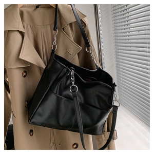 Detail of black PU leather tote bag featuring pleated design and silver metal chain links