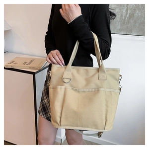 Detail of khaki canvas tote bag featuring large front pockets and adjustable shoulder strap