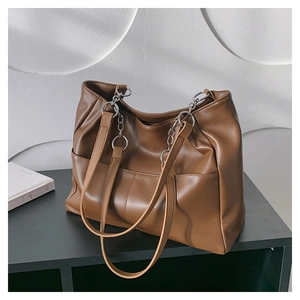 Detail view of the caramel brown tote bag showing supple faux leather and chain strap