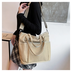 Close-up of khaki canvas tote bag with functional outer pockets and adjustable strap
