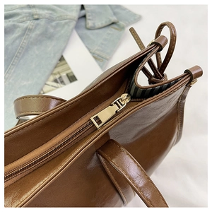 Detail einer braunen Ledertasche mit glattem Reißverschluss und gestreiftem Innenfutter