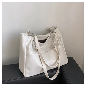 Detail of soft cream tote bag featuring front dual pockets and silver metal chain strap