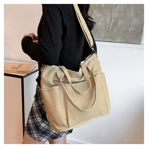 Detail of a khaki canvas tote bag with multiple pockets and adjustable shoulder strap