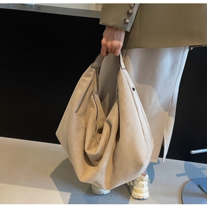 Close-up of large beige hobo tote bag with zipper detail and soft suede texture