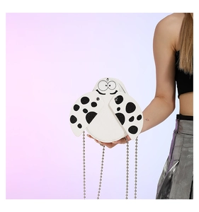 Detailed close-up of white ladybug pattern PU leather bag with black polka dots and silver chain