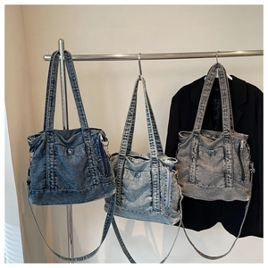 Detailed view of three denim tote bags in blue and grey hanging on a metal rack