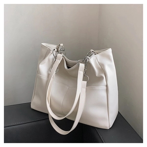 Close-up of a cream oversized tote bag with soft leather texture and front pockets
