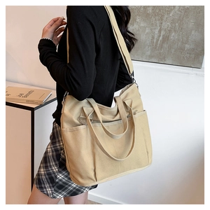 Detail of beige canvas tote bag with long shoulder straps and large external pockets
