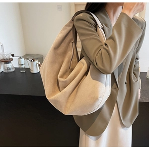 Detail of minimalist beige suede hobo bag with zip showing natural drape and soft texture