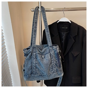 Detail of blue denim tote bag with front pocket and shoulder straps on blazer