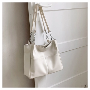 Close-up of cream white PU leather tote bag with metal chain strap and front pockets