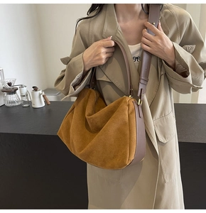 Caramel suede hobo bag shown as shoulder style on model in a cozy cafe setting