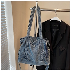 Detail of vintage blue denim tote bag featuring metal snap pocket and side zipper accents