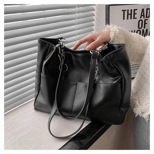Detail of black tote bag with vertical pockets and stylish chain-leather shoulder strap