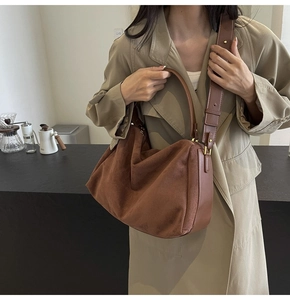 Close-up of caramel brown suede baguette bag with leather strap and metal buckle detail