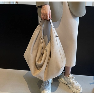 Detail view of large beige suede tote bag featuring side metal zipper and magnet closure