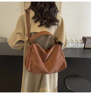 Detail of a brown suede hobo bag with vintage matte finish and wide leather strap