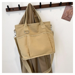 Detail of khaki heavy-duty canvas tote with dual front pockets and adjustable strap