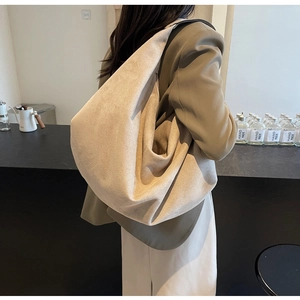 Minimalist beige suede hobo bag shown on a model highlighting its large capacity and soft silhouette