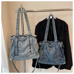 Detail of washed denim tote bags in light and medium blue with front buckle pockets