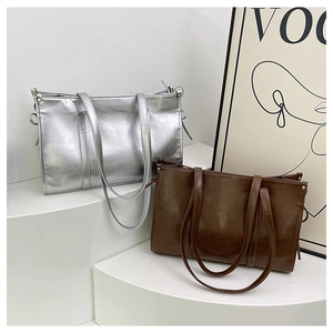 Minimalistische quadratische Tragetaschen in Silber und Braun auf weißem Sockel