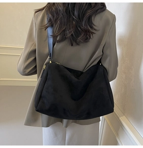 Detail view of large black suede shoulder bag with gold hardware on a model