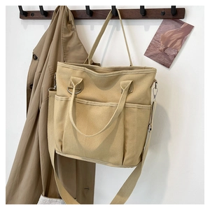 Detail of khaki heavy-duty canvas tote bag featuring multi-pocket design and adjustable strap