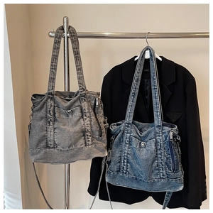 Detailed close-up of washed denim tote bags in grey and blue with metallic zippers
