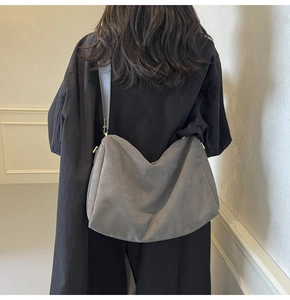Macro detail of large grey suede baguette bag showing the matte texture and shoulder strap