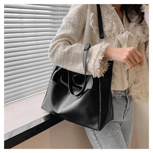 Close-up of black glossy PU leather tote bag with soft folds and silver ring details