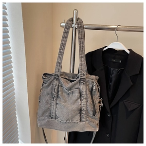 Detail view of washed grey denim tote bag with metal zipper and front pocket design