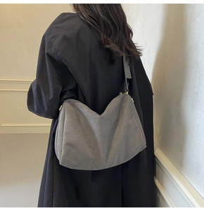 Detail of grey suede hobo bag featuring soft texture and gold cylinder metal buckle