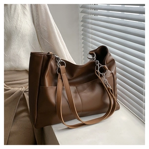 Detail of a large brown matte leather tote bag with silver rings and visible stitching
