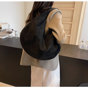 Side view of large black suede hobo bag on shoulder showing texture and capacity