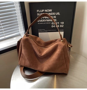 Detailed close-up of dark brown suede baguette bag with smooth leather strap and gold zipper