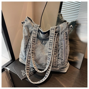 Detail view of washed denim tote bag featuring metal snap pocket and vertical side zipper