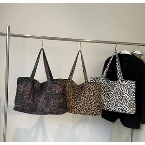 Detailed macro view of large leopard print tote bags in three colors hanging on metal racks