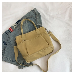 Macro view of khaki canvas crossbody bag with front pocket and adjustable shoulder strap